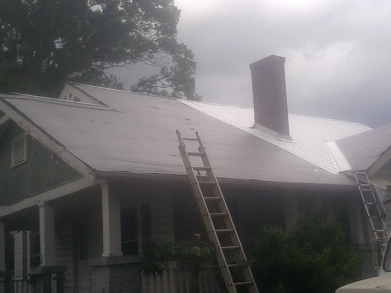 Ladders against a metal roof on an older home with a brick chimney in Scotland