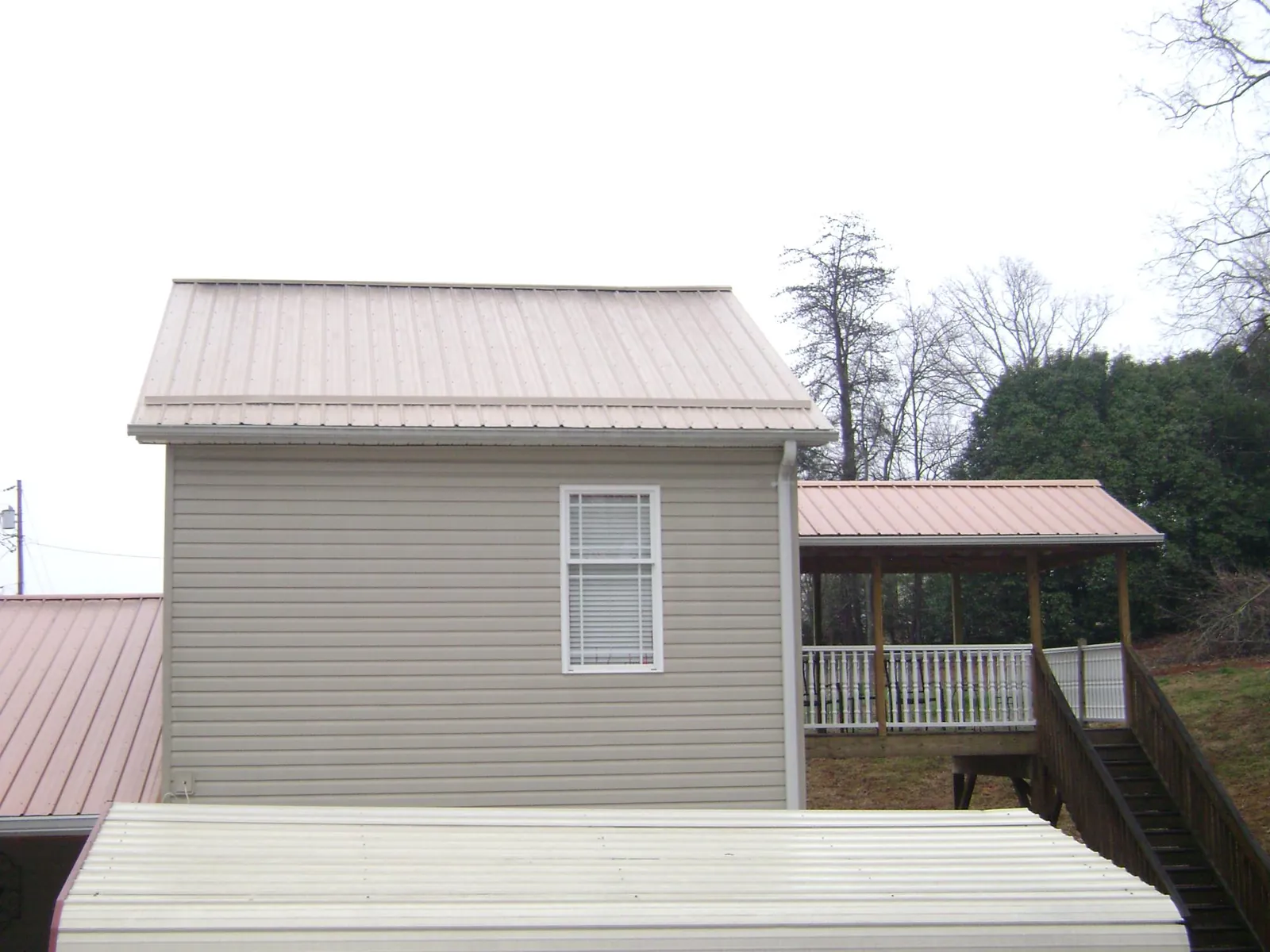 Tan metal roofs on a two story addition and attached porch, from a Roof Replacement job in Scotland
