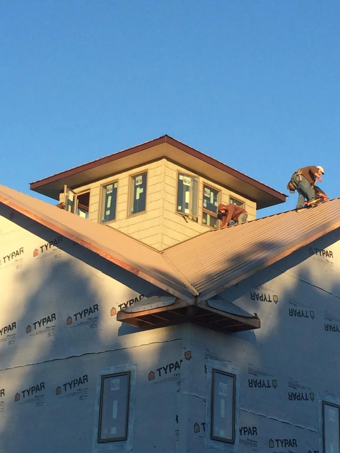 Roofers working around a rooftop cupola on a new metal roof at sunset — Roof Waterproofing in Scotland by Roofing Brothers